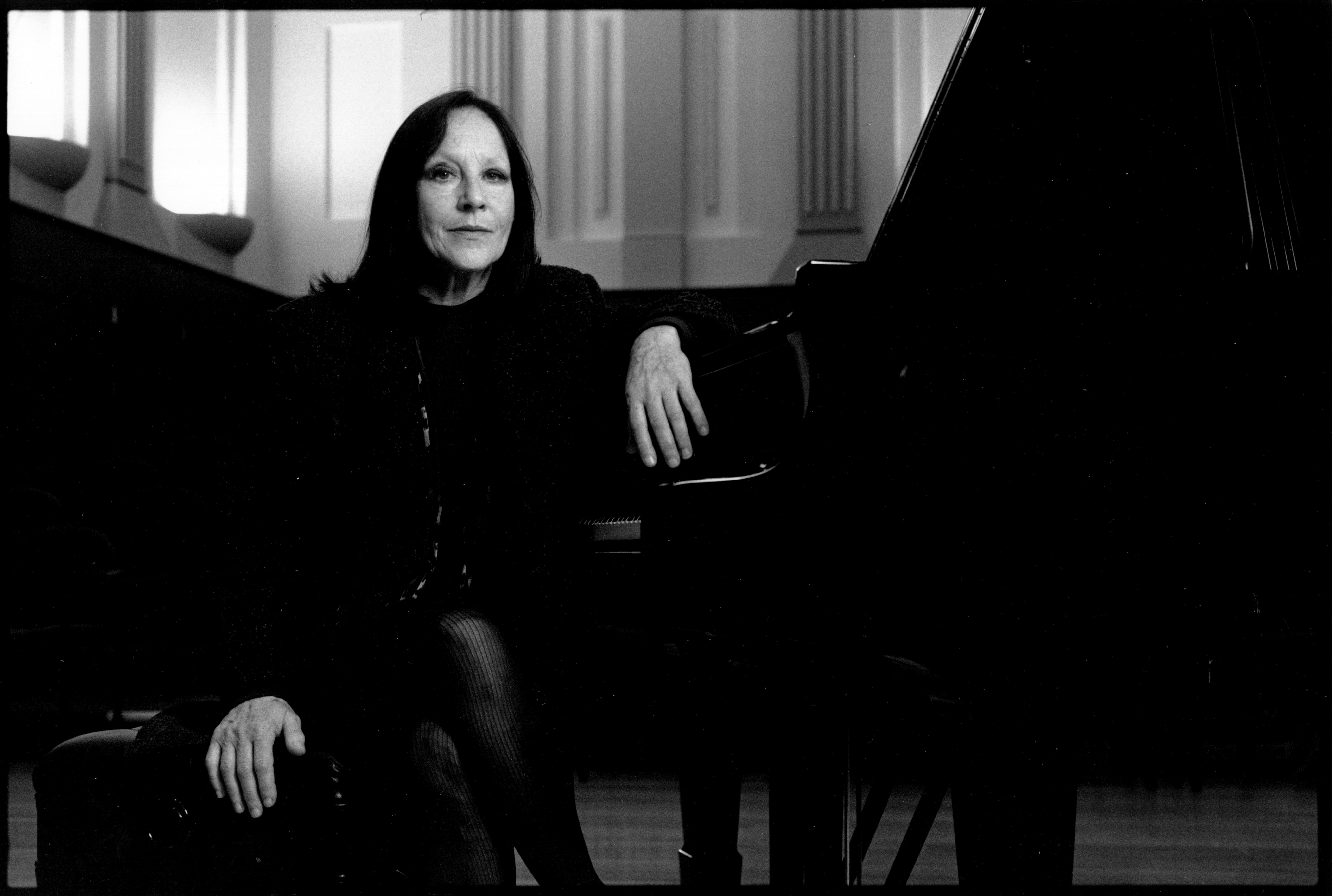 Black and white photo of Dr Judy Bailey OAM sitting at a piano