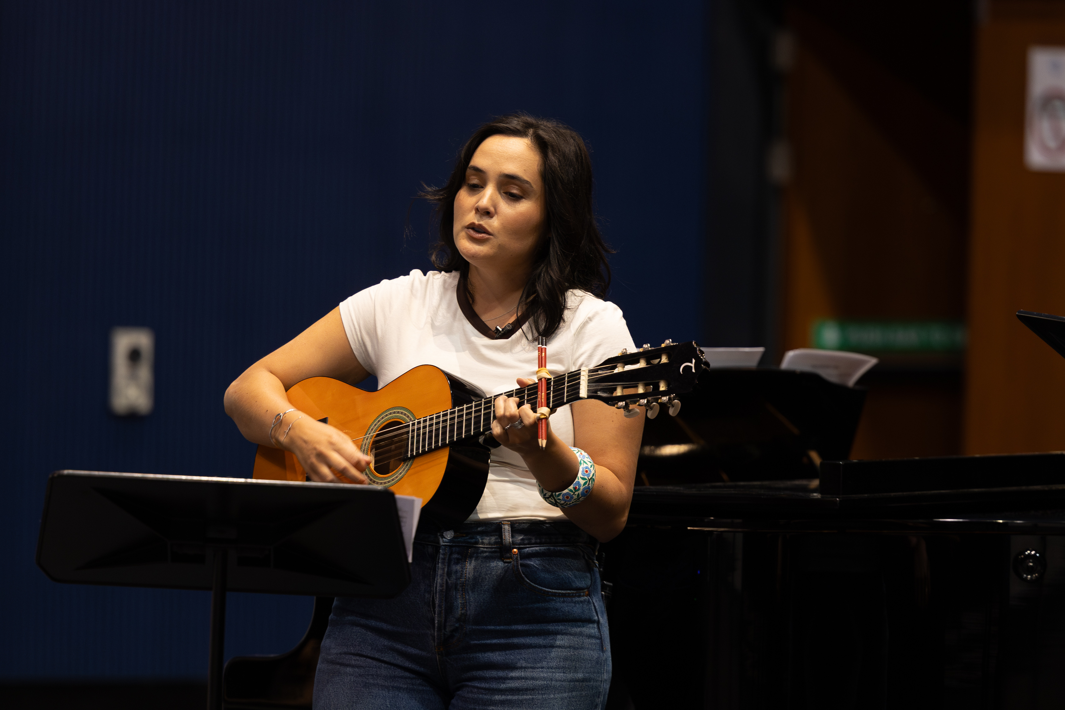 A photo of a musician in the studio holding an acoustic guitar.