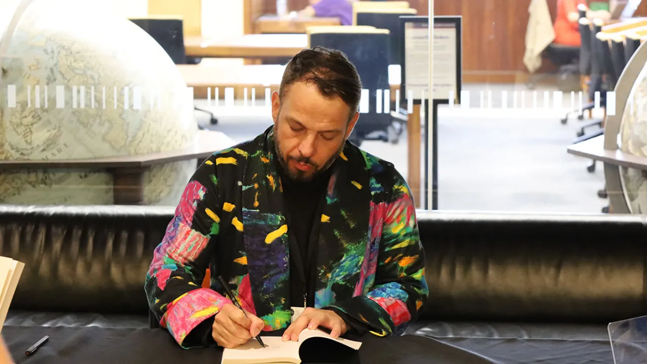 Scott-Patrick Mitchell signing copies of Clean at the 2023 PMLAs