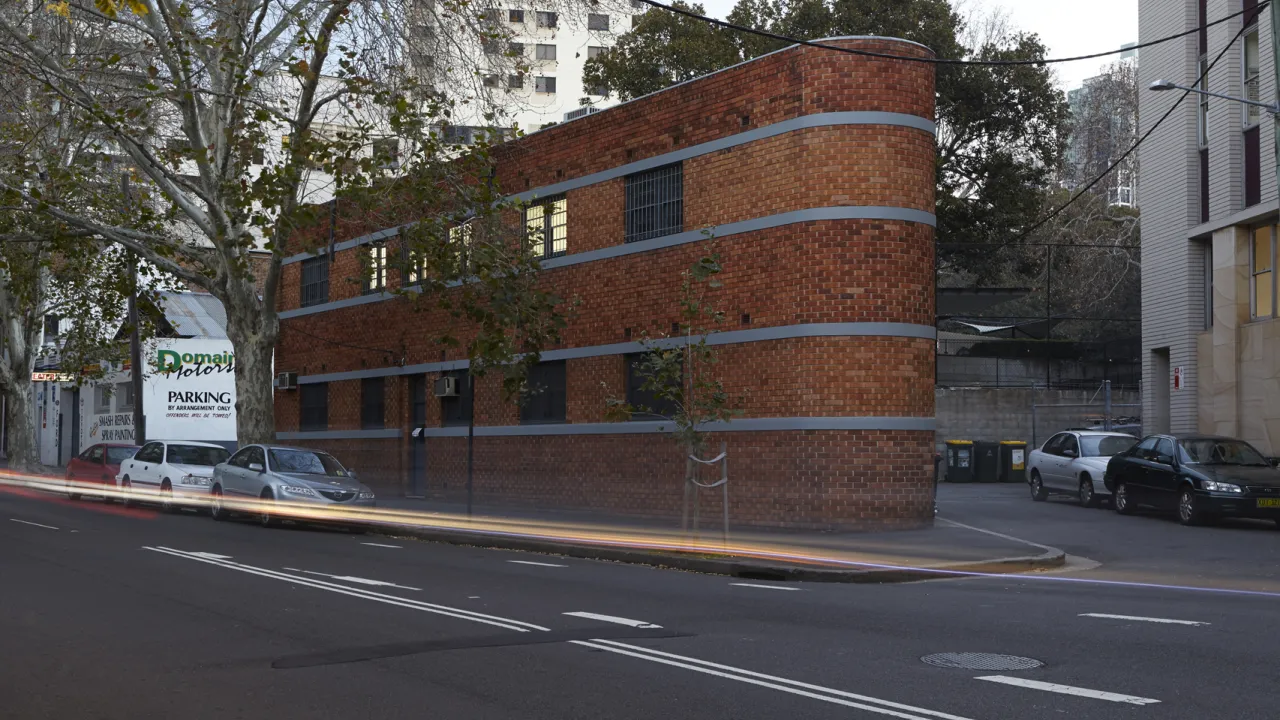 street front of a two storey red brick building with cars parked outside
