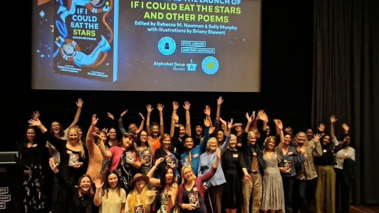 A large group of writers pose on the stage of the State Library of WA theatre. They hold copies of If I Could Eat the Stars with their hands in the air, celebrating. On the screen above them is a holding screen featuring the cover of the book.