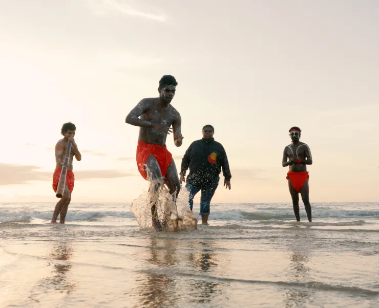 First Nations performers on a beach