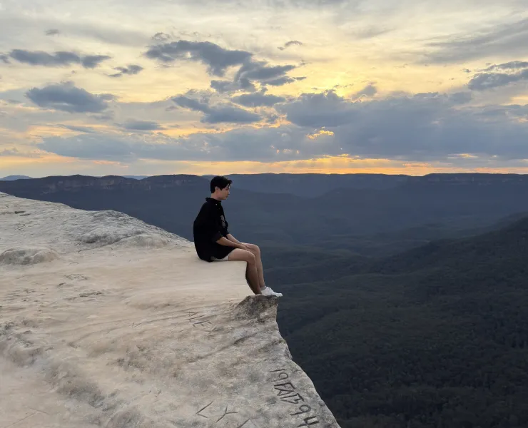 Naraphat Sakarthornsap sits on the edge of a cliff at dusk