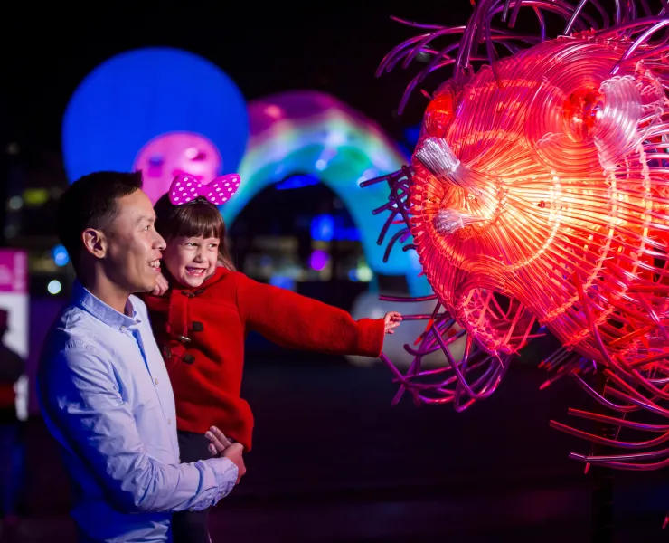 Family enjoying a close-up view of the Fugu light installation at First Fleet Park, The Rocks during Vivid Sydney 2018