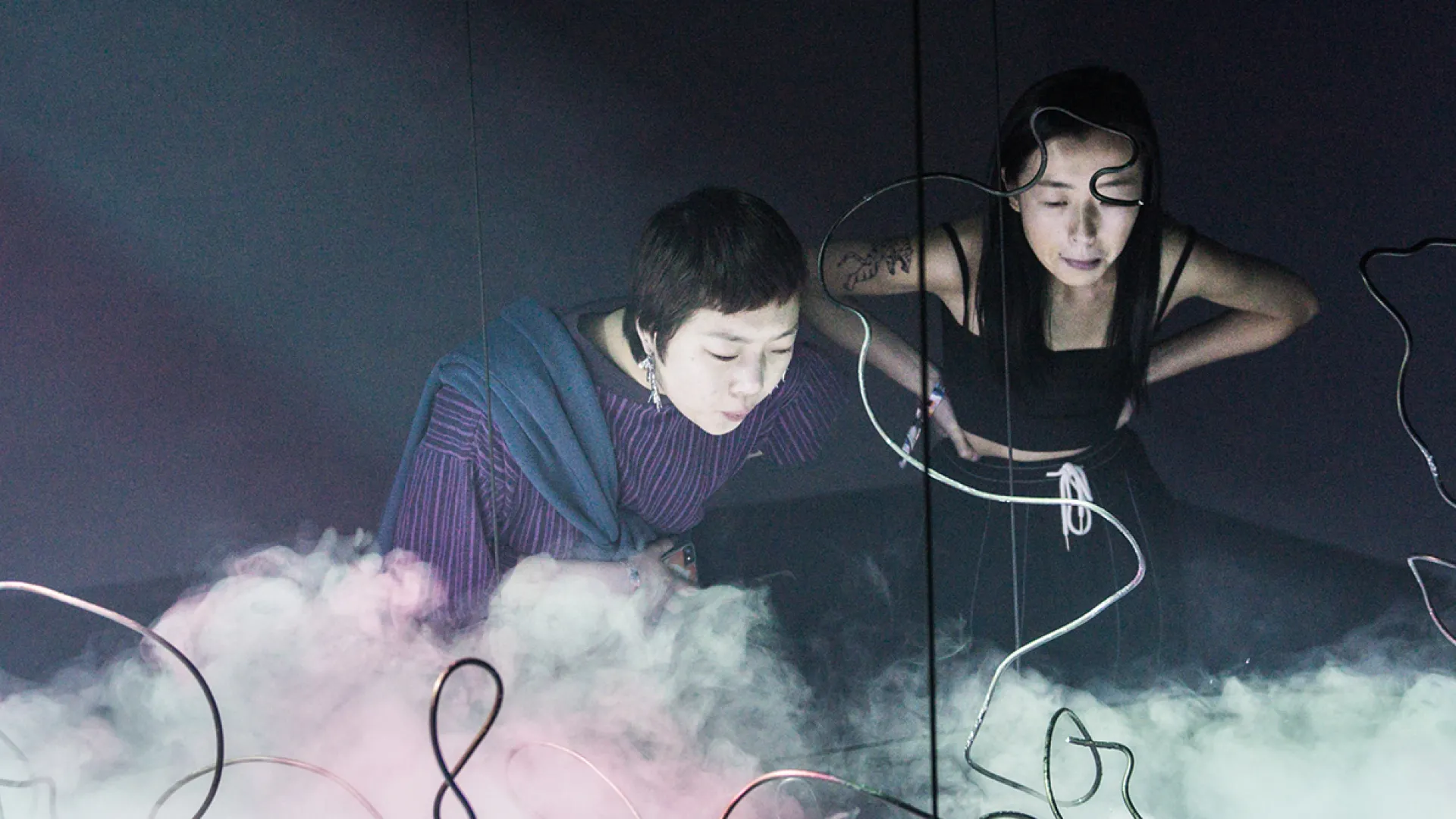 Two women looking at an art installation with dry ice